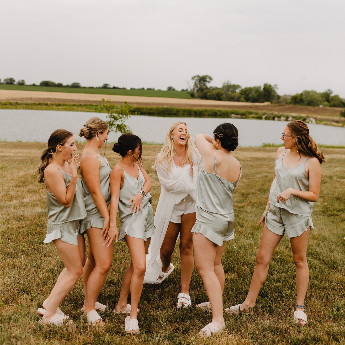 Group of women in matching outfits standing in a field with a lake in the background
